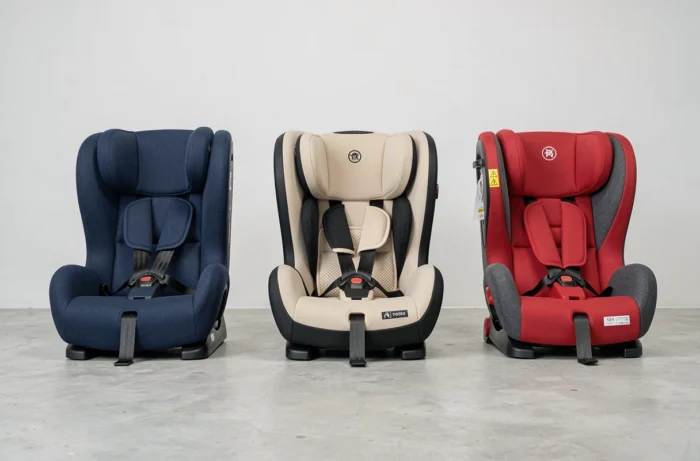 Comparaison de trois sièges auto groupe 1 2 3 aux designs différents posés côte à côte dans un showroom, montrant les différences de confort et de sécurité